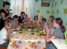 Ірина Раранчук (ліворуч) із чоловіком Миколою (в центрі) та дев’ятьма дітьми, які повернулися зі школи, моляться перед обідом. Один із синів, Сергій, вголос дякує Богу за їжу і просить благословити день