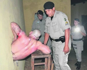 Охоронець допомагає 28-річному в’язню Рафаелю Валадау вилізти з отвору в стіні. Решта двоє сміються з чоловіка, який намагався втекти на волю, але через завеликий живіт застряв
