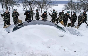 Солдати 17 грудня розчищають від снігу автомобіль біля міста Броди на Львівщині. Загалом на заході України упродовж 24 годин звільнили від снігу близько двох тисяч авто