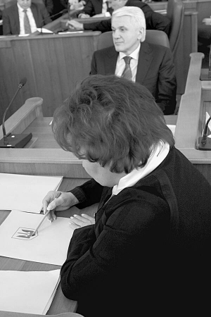”Регіоналка” Тетяна Бахтеєва олівцем розмальовує тризуб на зеленій теці під час засідання погоджувальної ради 9 січня