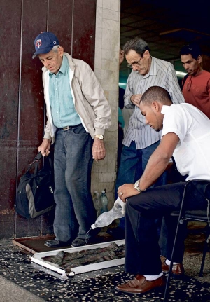 Робітник наливає дезінфікат у таці на зупинці автобуса в столиці Куби Гавані. Пасажири знезаражують у них підошви, перш ніж увійти до автобуса