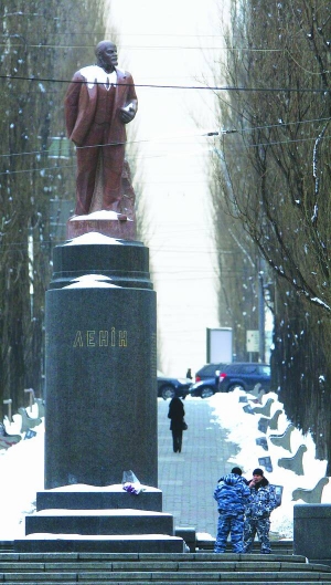 Троє чоловіків у камуфляжній формі у вівторок, 12 березня, стоять біля пам’ятника Володимирові Леніну в Києві. Вони заперечують, що охороняють Ілліча, хоча двоє з них протягом трьох годин не відходили від монумента