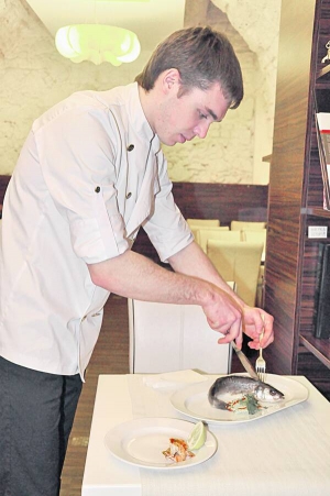 Кухар львівського ресторану ”Манускрипт” Олег Шрамко викладає запеченого сібаса та креветки на тарілку. Цю страву замовляють найчастіше