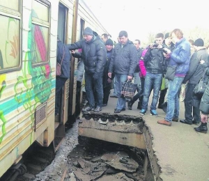 Люди перестрибують через обвалену плиту на столичній станції ”Вишгородська” 2 квітня. Так заходять до вільного вагона електрички, бо інші переповнені
