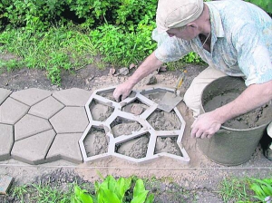 Василь Павленко за допомогою спеціальної форми кладе доріжку з бетону на власній дачі