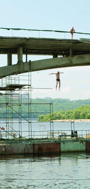 Чоловік стрибає з мосту на столичному Гідропарку. Після паводку санепідемстанція дозволяє купатися лише на пляжі ”Дитячий”. Не рекомендують робити це на десяти пляжах Києва
