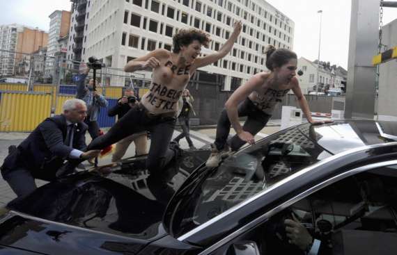 Активістки руху FEMEN встрибують на капот автомобіля під час акції протесту проти візиту прем'єр-міністра Тунісу Алі Лараеда біля будівлі Європейської комісії у Брюсселі, Бельгія, 25 червня 2013