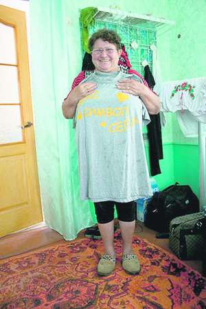 Оксана Косінська прикладає до грудей футболку з написом ”Секс-символ села”. Її подарували після концерту ансамблю ”Лісапетний батальйон”, в якому жінка співає