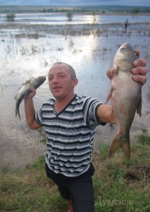 Чоловік показує зловлену руками рибу серед поля біля села Веселий Кут Арцизького району Одещини. Через паводок прорвало дамбу місцевого рибного господарства
