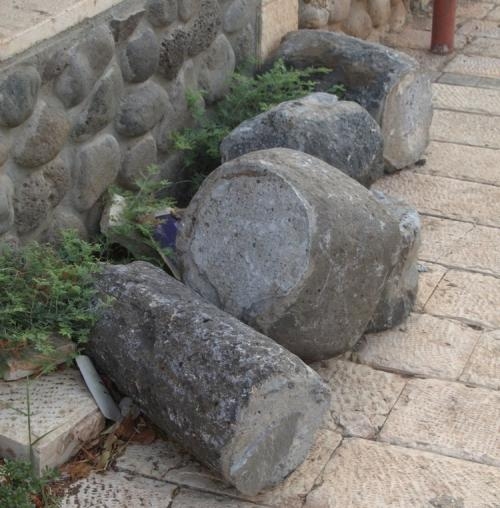 Фрагменти римської колони і камені для перемелювання зерна на тлі сучасної бруківці