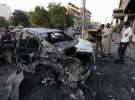 Люди дивляться на автівку, яка вибухнула в Багдаді 