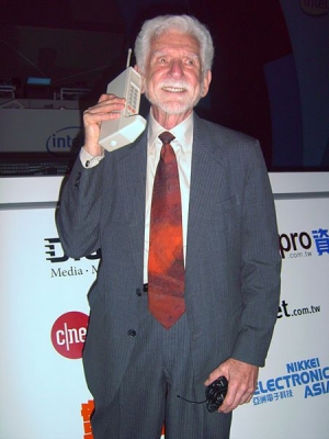 Мартін Купер в 2007 році. У руках одна з перших моделей стільникового телефону
