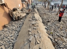 Развороченная дорога и опрокинутый автомобыль на месте взорвавшегося нефтяного трубопровода. Погибло 22 человека. Китай, Циндао, 22 ноября 2013.
