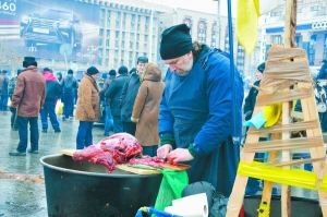 Чоловік на майдані Незалежності в Києві ріже м’ясо. У наметовому містечку готують страви, якими годують мітингувальників