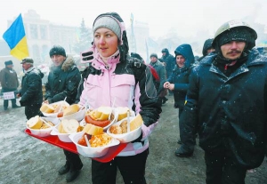 Жінка розносить кашу з м’ясом та хлібом біля Будинку профспілок, що на майдані Незалежності в Києві. Тут два тижні працюють польові кухні на колесах