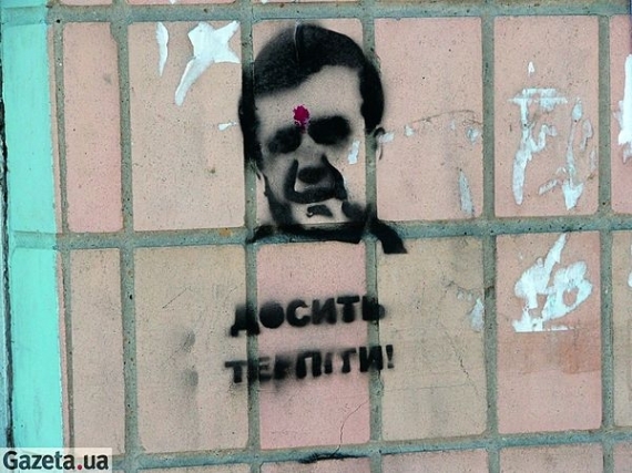 У графіті, що зображує голову чоловіка з червоною цяткою на лобі, українські правоохоронці розгледіли портретну схожість із президентом Віктором Януковичем. Цятку потрактували як кривавий слід від пострілу
