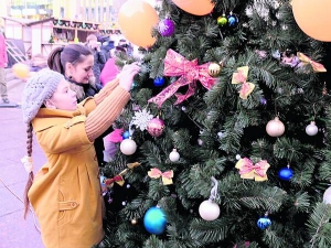 Діти прикрашають ялинку біля Національної опери в центрі Києва. Її встановили 24 грудня