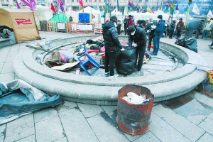 9 січня чоловіки прибирають на Майдані намет мітингувальників. Брудний одяг кладуть у сміттєві мішки, мокрі від дощу ковдри сушать