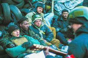 Протестувальники відпочивають під барикадою на столичній вулиці Грушевського. Один з активістів співає під гітару