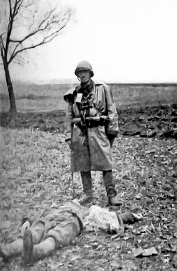 Вояк із польської партизанської Армії крайової позує над трупом українського селянина, убитого в полі коло села Сагринь на Холмщині, березень 1944 року