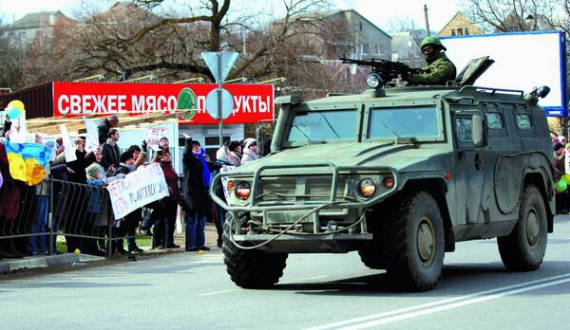 Противники приєднання до Росії у Сімферополі спостерігають, як містом їде броньований автомобіль із російськими військовими. 10 березня 2014 року
