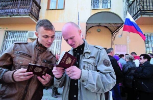 Минулого четверга у Сімферополі чоловіки роздивляються російські паспорти, які щойно отримали. Біля офіса федеральної міграційної служби щодня збираються черги