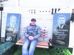 Чоловік сидить між надгробками екс-президента Віктора Януковича та колишнього прем’єра Миколи Азарова. Ім’я замовника агентство ритуальних послуг не називає