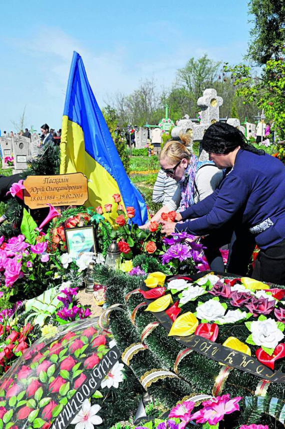 Дружина і мати кладуть троянди на могилу Героя Небесної сотні Юрія Пасхаліна у селі Носачів Смілянського району Черкащини