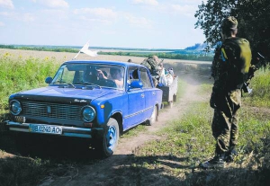 Солдат із добровольчого батальйону ”Айдар” спостерігає, як місцеві жителі залишають селище Металіст Слов’яносербського району на Луганщині 11 липня. У понеділок українські військові звільнили цей населений пункт від терористів