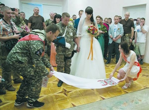 Російський терорист Арсен Павлов із нареченою Оленою Колєнкіною стають на рушник щастя у центральному Донецькому загсі. Гості прийшли на їхнє весілля у камуфляжі та зі зброєю