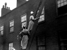 Члени жіночої пожежної команди на пожежній драбині з пожежними рукавами і вогнегасниками, 1916