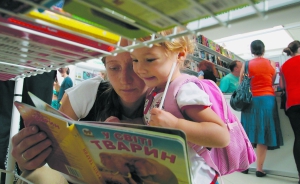 Відвідувачі Форуму видавців у Львові розглядають дитячу книжку ”У світі тварин” на ярмарку у Палаці мистецтв 12 вересня