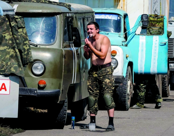 Український вояк голиться біля машини, що стоїть у колоні військової техніки в місті Волноваха на Донеччині