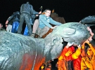 Люди відколюють шматки від статуї радянського вождя Володимира Леніна. Пам’ятник повалили протестувальники після проукраїнського мітингу в Харкові. Монумент простояв у обласному центрі 51 рік