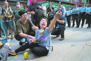 Протестувальниця плаче перед рядом поліцейських на заблокованій дорозі. Перед тим поліція зруйнувала барикади у районі Гонконгу Монгкок