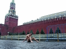 Художник Петро Павленський сидить на Красній площі в Москві з прибитими до бруківки геніталіями 10 листопада 2013 року. Неподалік стоять поліцейські, які не знають, як реагувати на оголеного чоловіка   