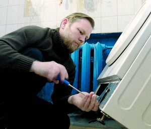 Переселенець із Криму Олексій Клепіков ремонтує пральну машину в квартирі біля столичної станції метро Університет. Щодня отримує чотири-п’ять замовлень