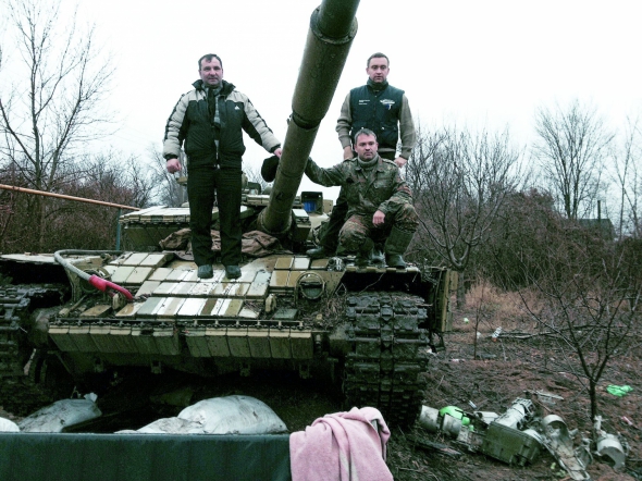 Волонтер Тарас Елейко (у центрі, присів) під час відвідин добровольчого корпусу "Правого сектора" та 93-ї танкової дивізії Збройних сил України в селі Піски під Донецьком, 25 грудня 2014 року. Ліворуч – отець Орест Чекан із міста Винники біля Львова, їздив в АТО як капелан. Праворуч – Богдан Шустер із Винників – член Всеукраїнського волонтерського руху