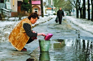 Жінка збирає воду з калюжі у відро в Донецьку, 31 січня. За вихідні в місті загинули 15 осіб, понад 30 — поранені