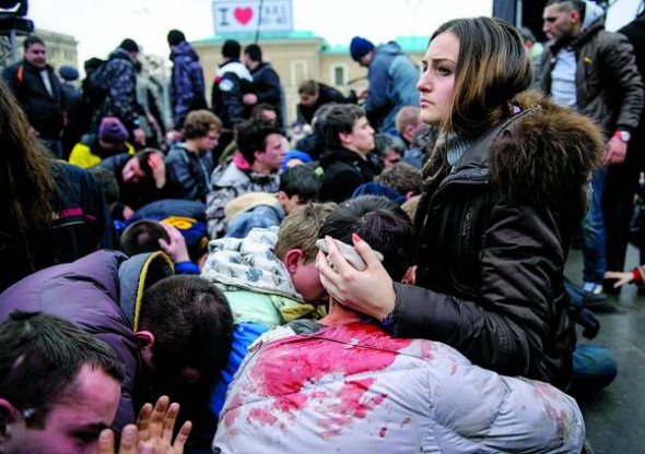 Побиті харківські євромайданівці після сутичок із проросійськими активістами в центрі міста сидять на землі в зоні, яку охороняє міліція, 1 березня 2014 року