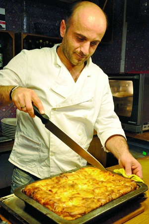 Шеф-кухар Леван Мепарішвілі розрізає гарячу ачму великим ножем, викладає на тарілки й подає. Рекомендує до страви червоне грузинське вино