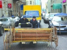 Двоє таджиків штовхають візок із металевими перекриттями на вулиці Старий Арбат в центрі Москви. Вихідці із Центральної Азії у столиці Росії працюють на найважчих роботах