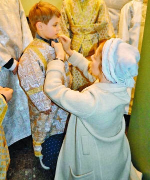 Співачка Тіна Кароль поправляє ризу на синові в Іллінській церкві на столичному Подолі. Дитина відвідує недільну школу при храмі