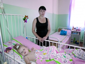 Альона Гохалтер із Вугледара на Донеччині стоїть біля ліжка доньки, 3-річної Альбіни. Дитина після операції має підвищену температуру і погано їсть