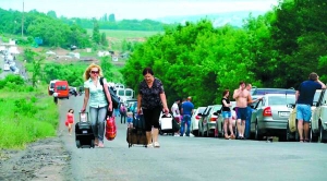 Жінки тягнуть сумки на коліщатках дорогою неподалік блокпосту біля міста Артемівськ на Донеччині. Правила перетину лінії розмежування стали жорсткішими. На пунктах пропуску утворилися черги з машин і автобусів завдовжки два–три кілометри