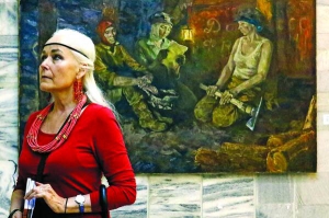 Відвідувачка фестивалю ”Донкульт” у Львові розглядає виставку у Палаці Мистецтв, присвячену Донбасу. Позаду — картина Ніни Марченко ”Жінки Донбасу”