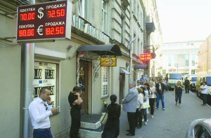 Люди стоять в черзі перед пунктом обміну валюти у центрі Москви в понеділок, 24 серпня. Більшість пунктів вивісили оголошення, що валюти в продажу немає. Деякі продавали не більше 200 доларів США в одні руки