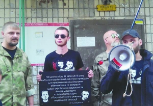 Активіст ”Правого сектора” тримає 26 серпня табличку неподалік будинку журналіста Олеся Бузини на вулиці Дегтярівській, 58, у столиці. На ній — портрети і прізвища Андрія Медведька й Дениса Поліщука — підозрюваних у його вбивстві. Попередню табличку, присвячену загиблому, збили невідомі 15 липня