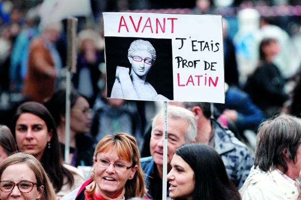 Жінка тримає плакат "Досі я був учителем латини" під час протестів у Парижі 17 вересня. Педагоги протестували проти освітньої реформи. Представники профспілки кажуть, що вона посилить конкуренцію шкіл