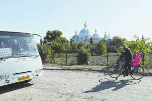 Житель містечка Угнів Сокальського району Львівської області везе дітей зі школи вулицею Зеленою. Автобус ”Ісузу” курсує з Рави-Руської. Тут ніде немає асфальту, дороги розбиті. Видно церкву Різдва Богородиці. У ній за графіком відправляють службу греко-католики і православні